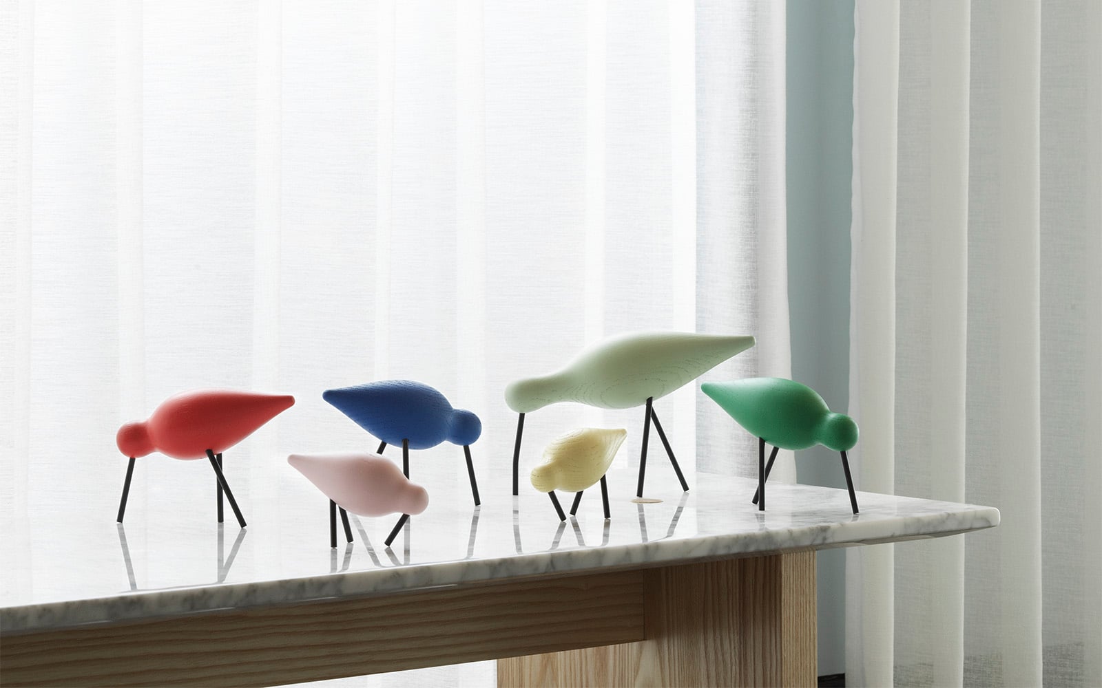 Shorebird - Red, Pink, Blue, Dusty green, Yellow and green - standing on a Solid Table - Normann Copenhagen